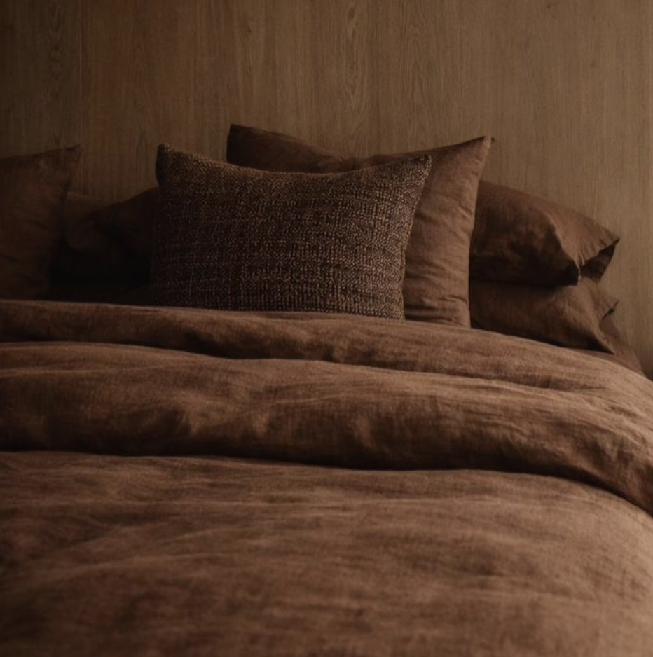 Roupa de cama em linho tingido em tom chocolate, travesseiros empilhados